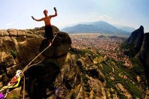 Praticante de highline entre formações rochosas acima de uma cidade.