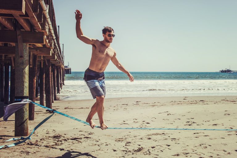 man standing on rope near beach